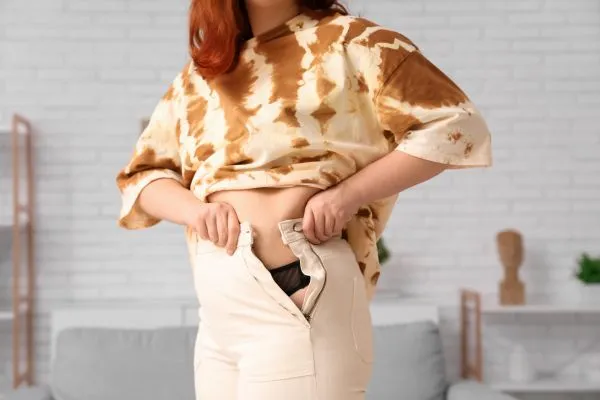 Image of woman trying to do her trousers up after pregnancy weight gain Hucknall